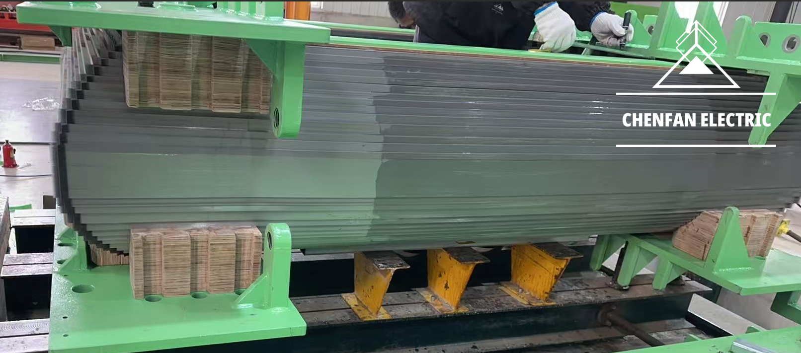 Stacked electrical-steel laminations beneath a green clamping frame